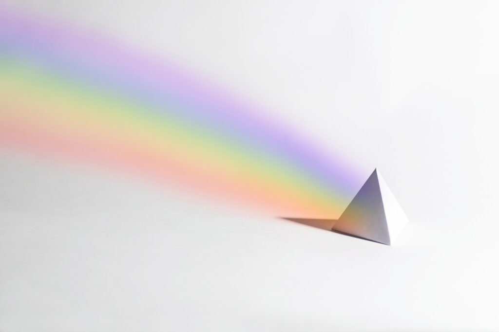 A white paper prism with drawn in colourful rainbow on a white background