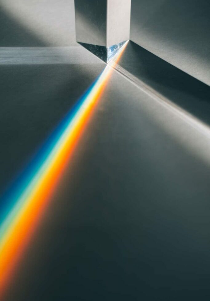 Bright shaft of sunlight passes through a glass prism creating a rainbow light effect